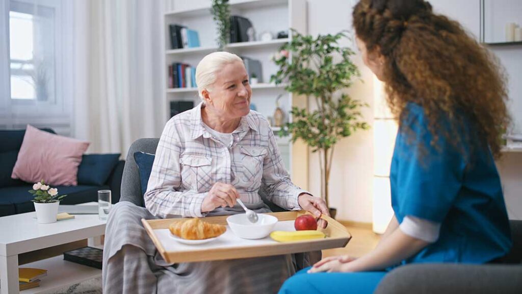 Older resident speaking with a family member in a bright assisted living common room