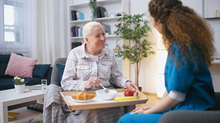 Older resident speaking with a family member in a bright assisted living common room
